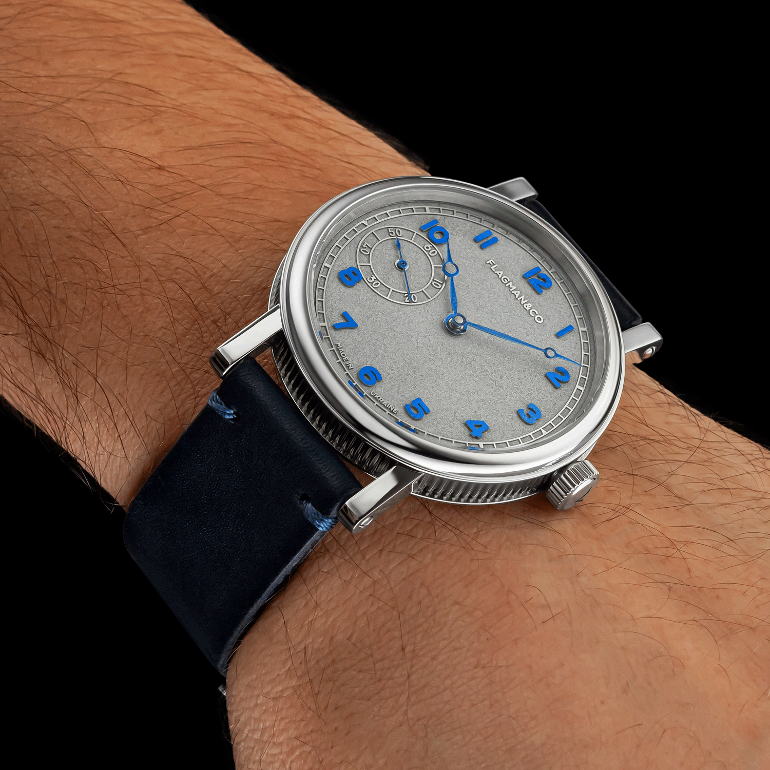 Handmade Watch with a blue strap and silver case on a wrist, brand name visible