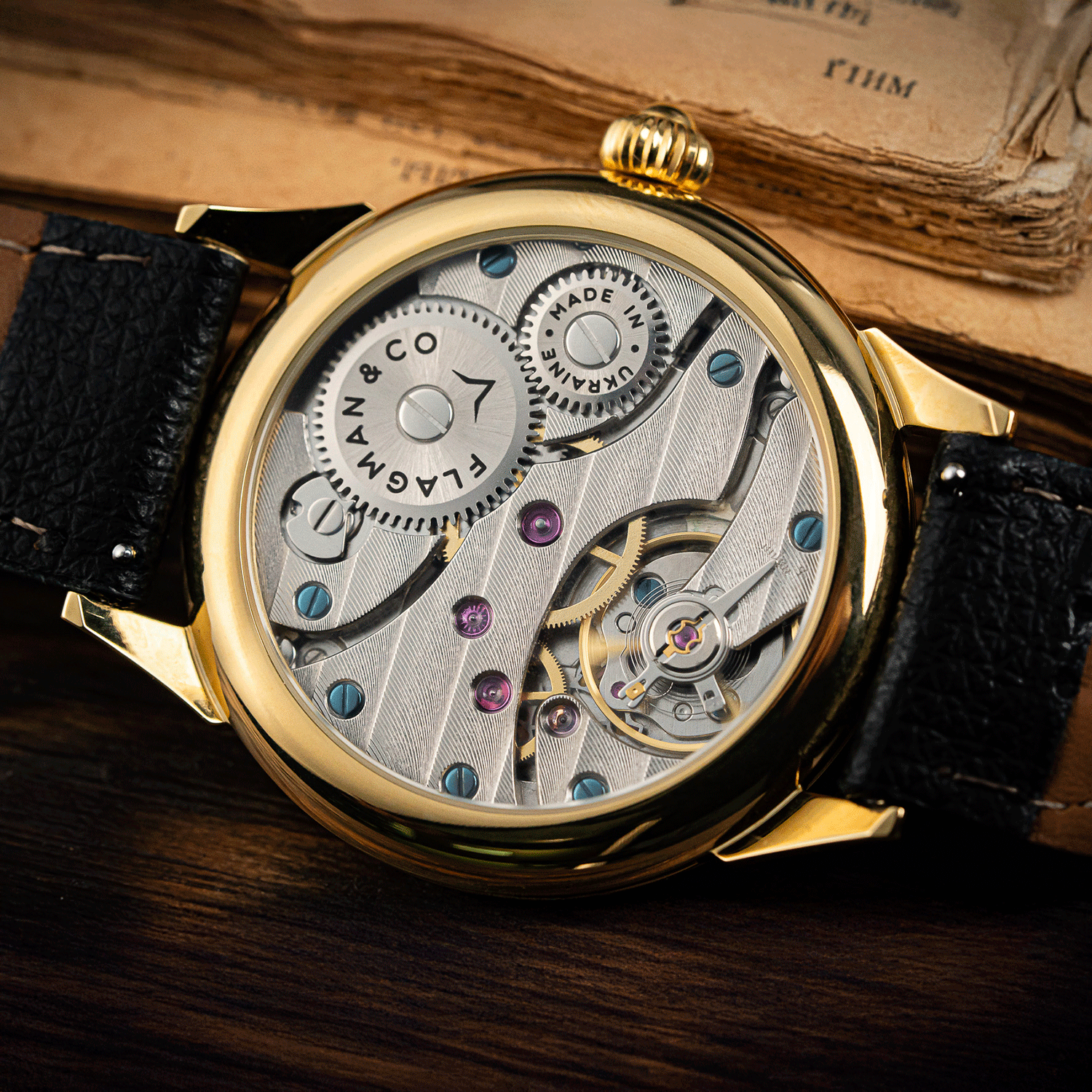 Mechanical wristwatch with black leather strap on an old book