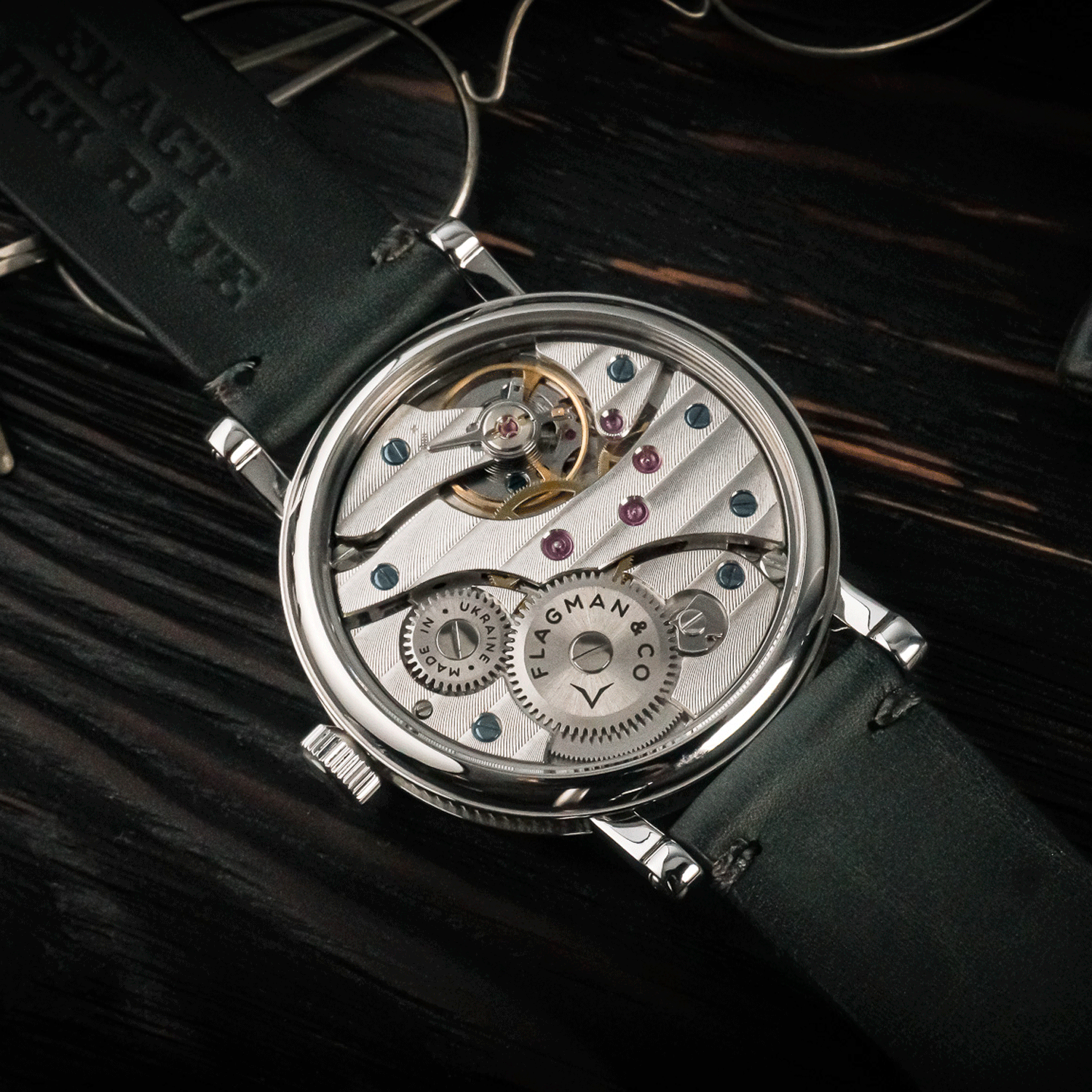 Close-up of a Flagman & Co watch with visible mechanical components on a dark background
