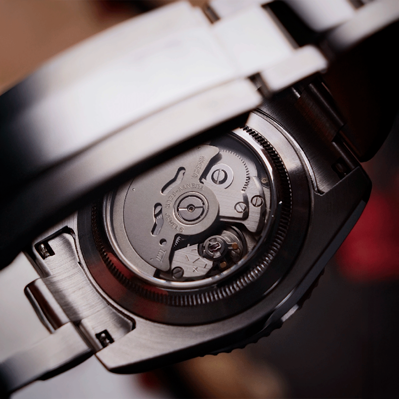 Close-up of a mechanical watch with open caseback showing intricate movement.