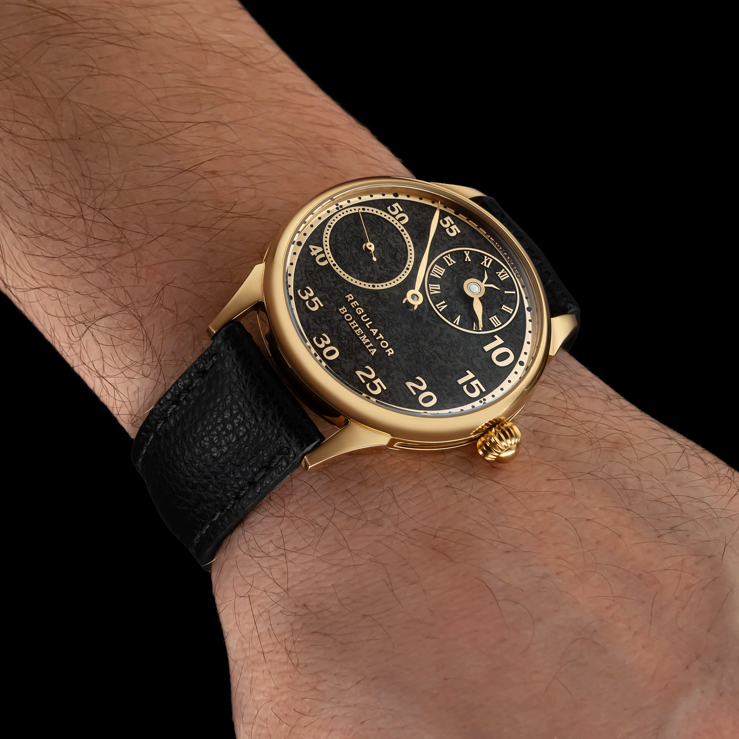 Mens wristwatch with black strap on a wrist against a black background