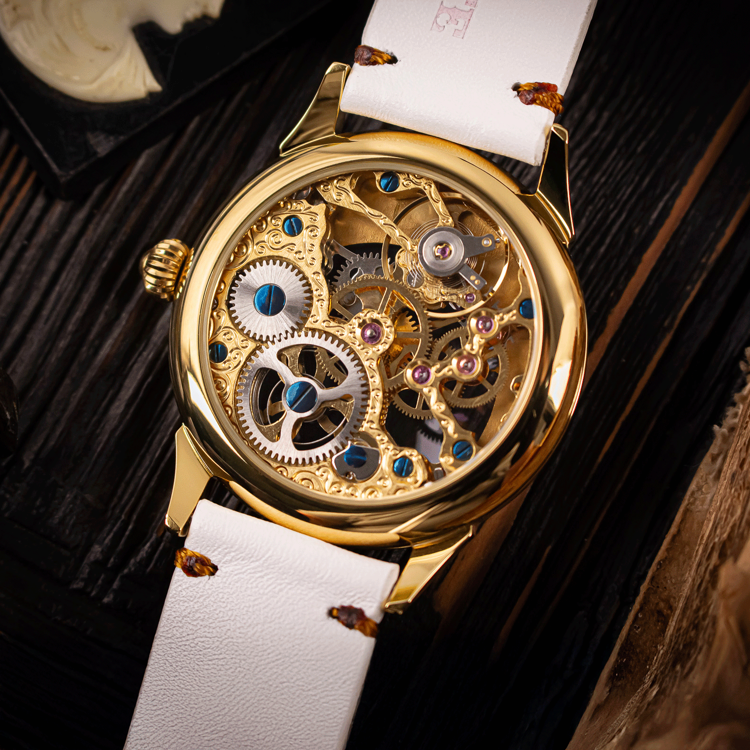 Skeleton mechanical watch with white strap on a dark textured background