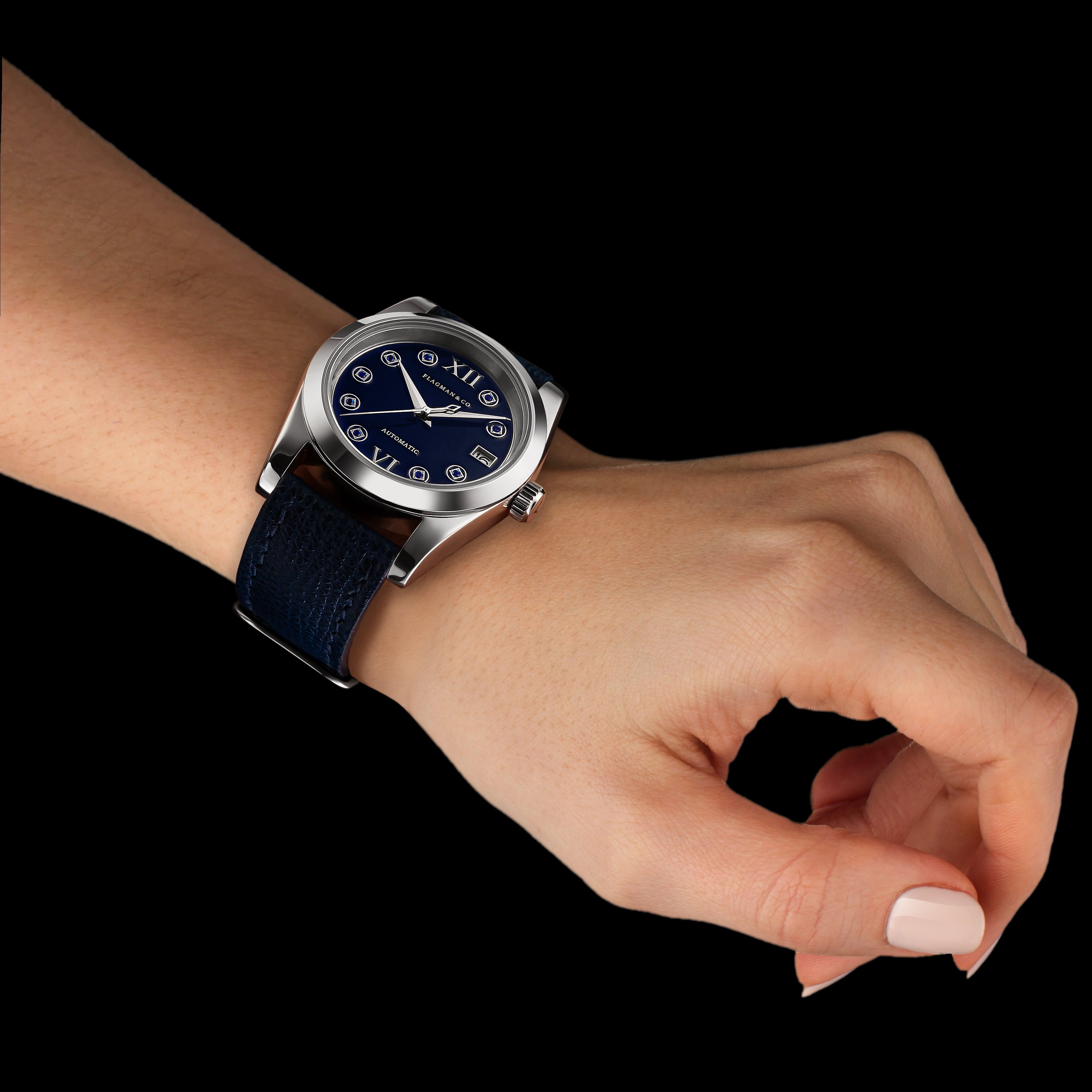 Hand wearing a watch with a dark blue strap and silver case on a black background