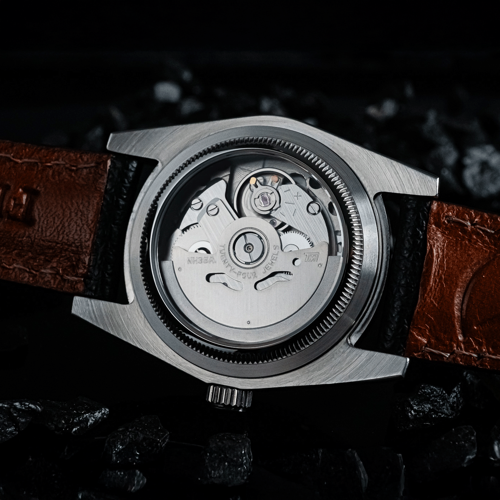 Watch with black leather strap and visible mechanical components on a dark background