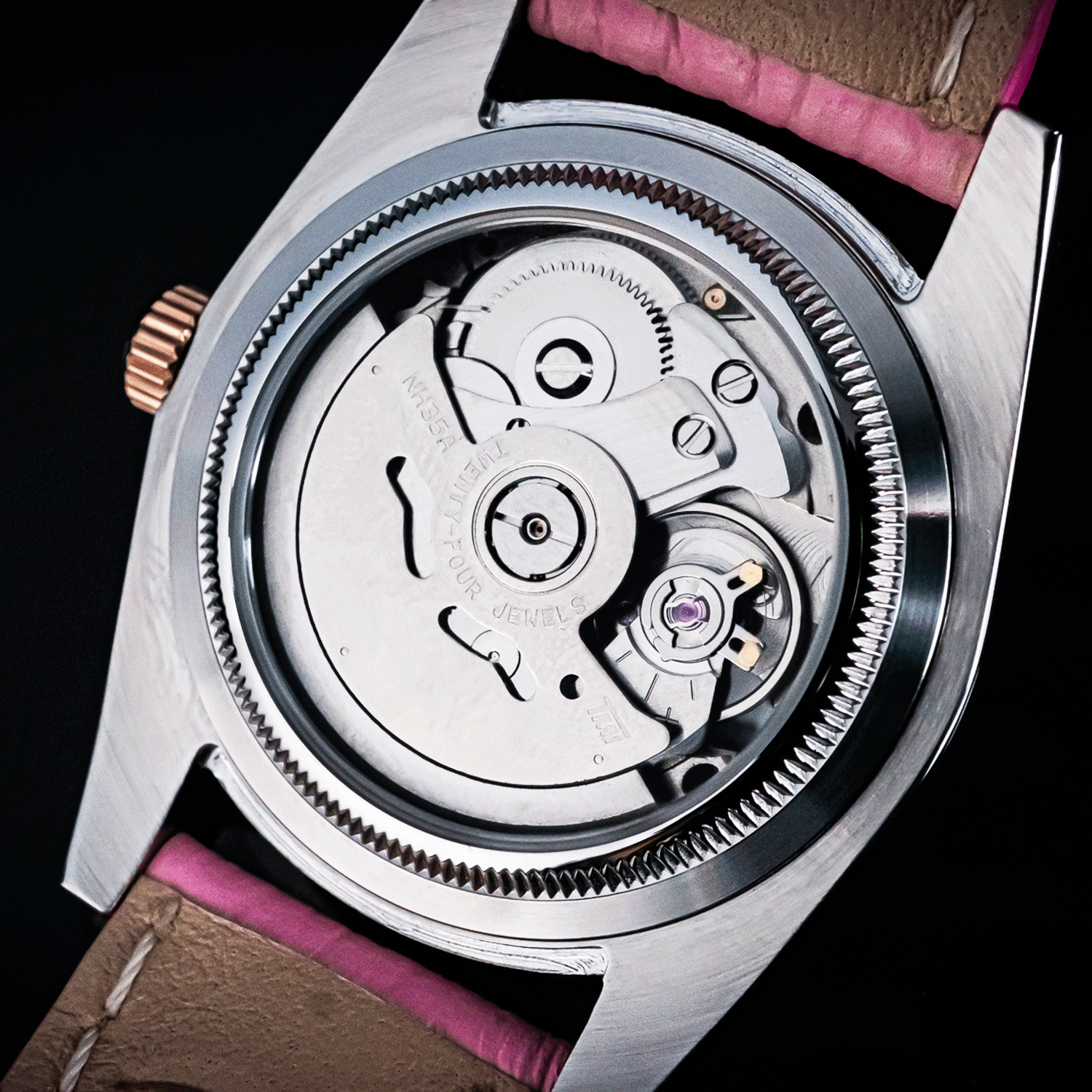 Close-up of a watch mechanism with a pink strap on a black background