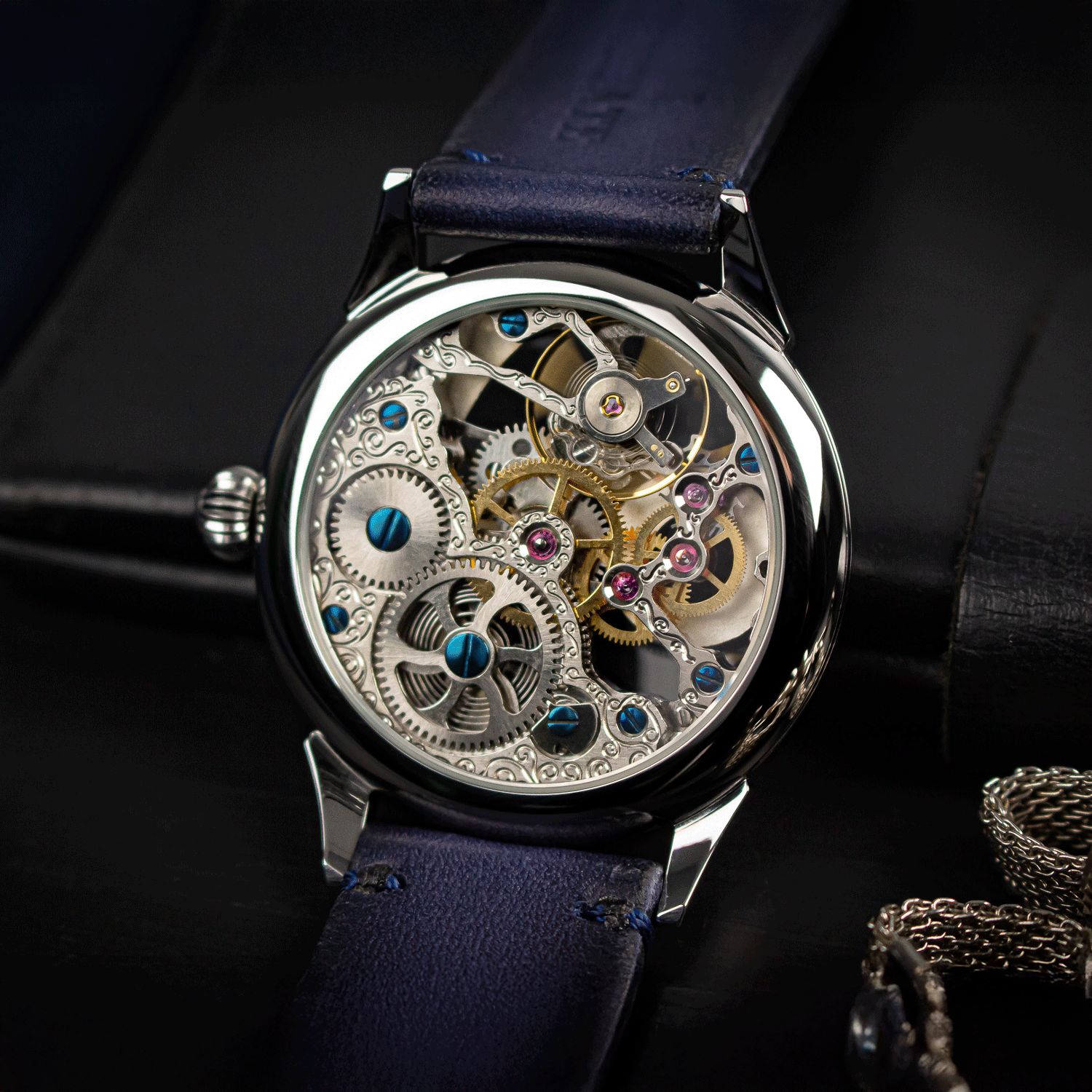Mechanical watch with visible gears and blue strap on a dark background