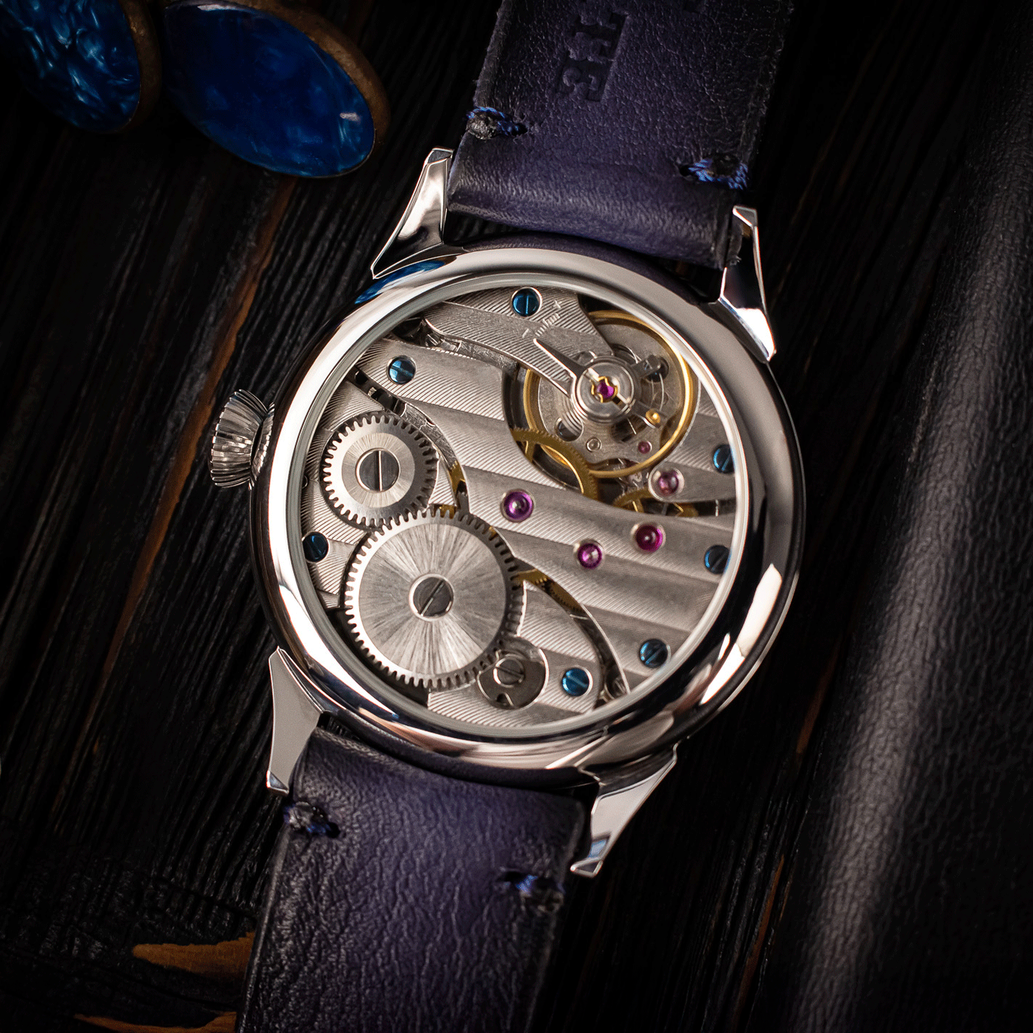 Close-up of a mechanical watch with visible gears and a dark blue leather strap.