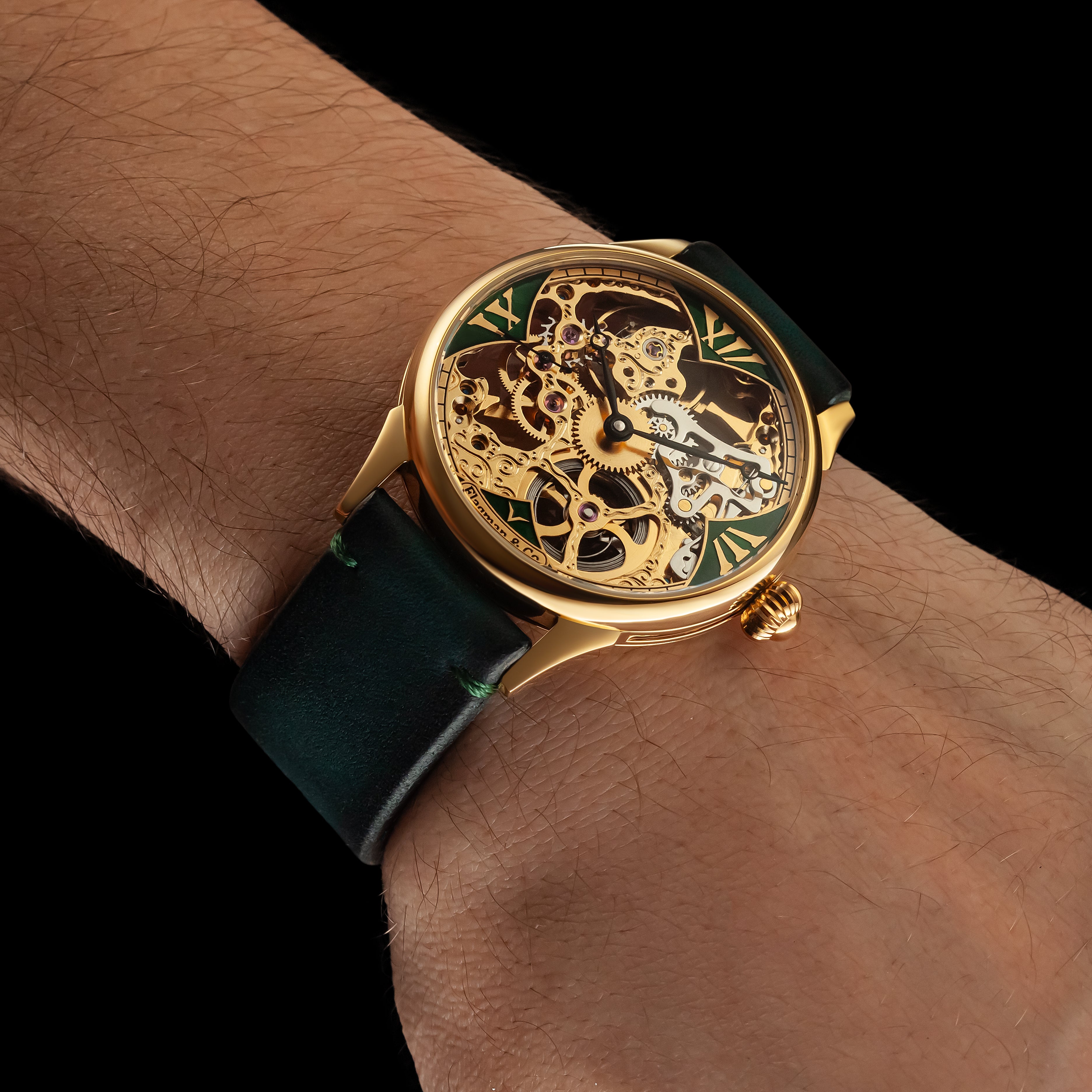 Gold wristwatch with green strap on a wrist against a black background