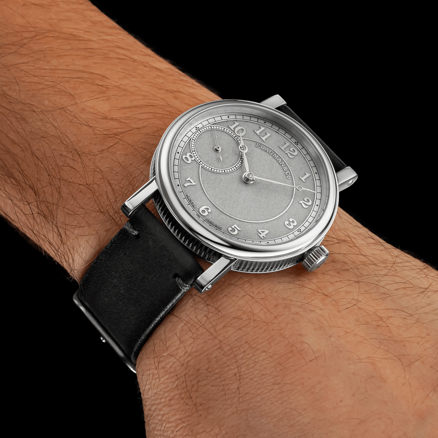 Vintage-style watch with gray strap on a wrist against a dark background